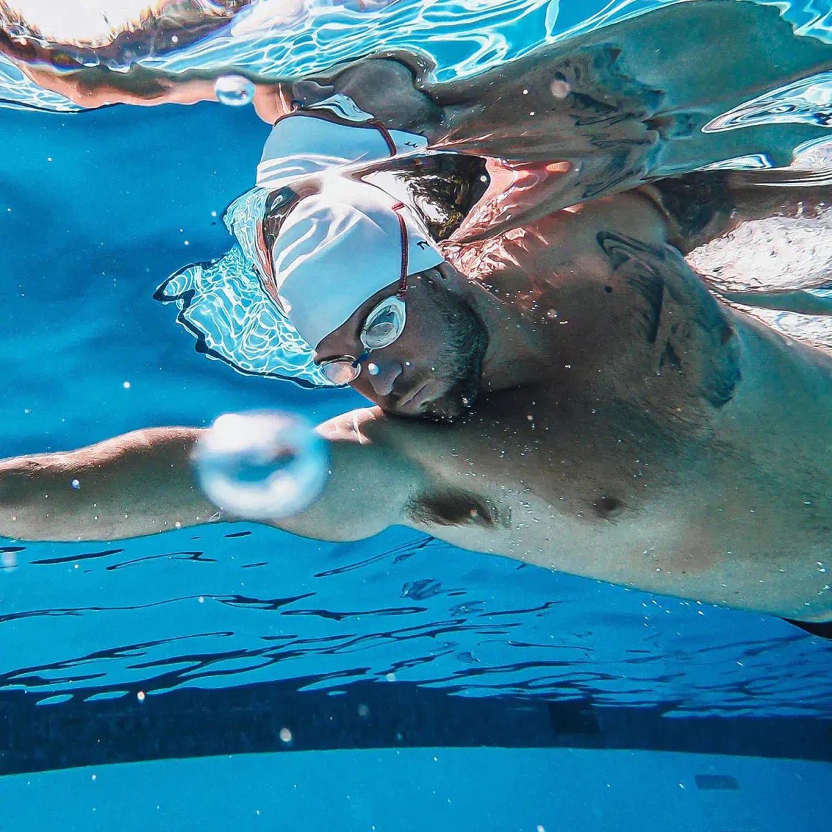 Mann schwimmt im Schwimmbad mit Schwimmbrille und -Kappe
