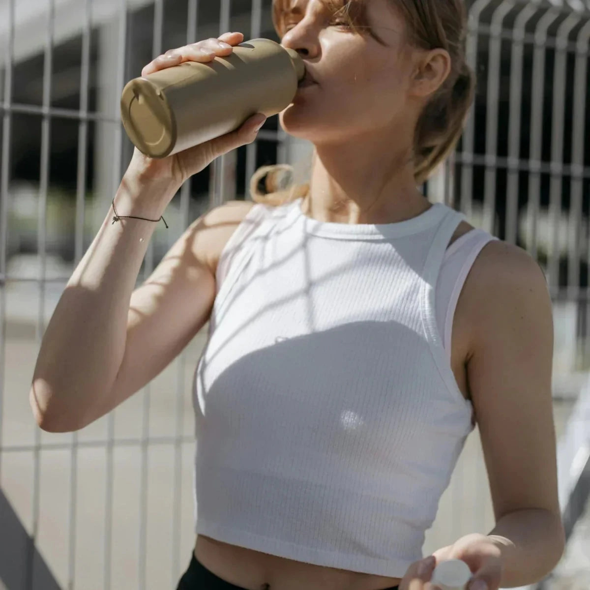 Kreatin Hydration: Frau trinkt bei Sport